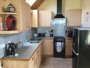 a kitchen with wooden cabinets and a black refrigerator at The Brae Steading in Fordyce