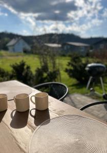 a wooden table with cups sitting on top of it at Domek Pod Gwiazdami Bieszczady in Hużele +6 photos