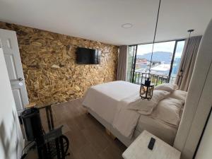 a bedroom with a bed and a tv on a stone wall at Casa colonial filandia in Filandia