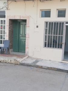 a green door on a white building with a chair at Luxury in El Haouaria