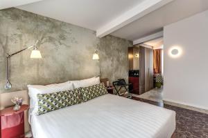 a bedroom with a white bed and a wall at Barberini 16- Boutique Hotel in Rome +36 photos