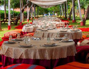 a row of tables with plates and glasses on them at Domaine Couleurs Berbères, Piscine, Vue Atlas, Bivouac & Expériences à Lalla Takerkoust in Lalla Takerkoust +49 photos