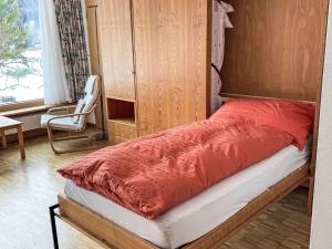 a bed with a red comforter and a chair in a room at Apartment Studio by Interhome in Bever