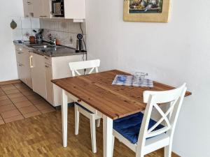a kitchen with a wooden table and white chairs at Apartment Studio by Interhome in Bever