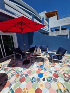 a patio with a colorful floor with a red umbrella at lagoon apartement 1 in Moulay Bousselham