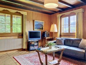 a living room with a leather couch and a tv at Apartment Chalet Clairval by Interhome in Charmey