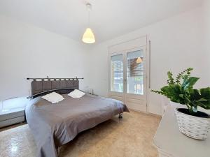 a white bedroom with a bed and a potted plant at Holiday Home Requesens by Interhome in Empuriabrava