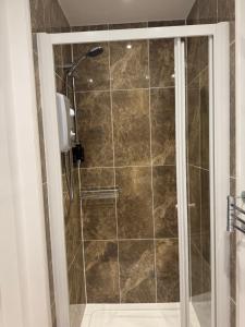 a shower with a glass door in a bathroom at Sandvilla Guesthouse in Oban