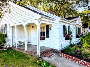 a small white house with a porch and flowers at Cape Cod Motor Inn in South Yarmouth