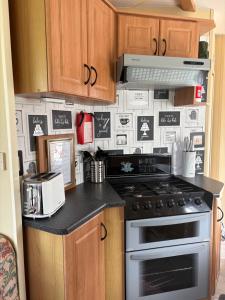 a kitchen with a stove and a wall covered in magnets at Jos caravan in Ingoldmells