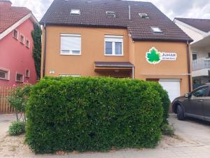 a house with a green hedge in front of it at Juhar Kiskunhalas in Kiskunhalas
