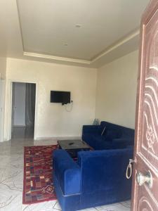 a living room with a blue couch and a tv at hôtel Kridane in Houmt Souk +3 photos
