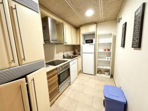 a small kitchen with white appliances and a blue stool at Two bedroom apartment behind the Rambla in Girona