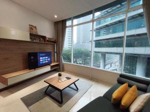 a living room with a couch and a tv and a table at Vortex Residence KLCC by Valen in Kuala Lumpur