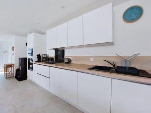 a kitchen with white cabinets and a clock on the wall at Holiday Home Ker Bernic by Interhome in Piriac-sur-Mer