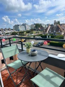 a table and chairs on a balcony with a view of a city at Appartement T2 - Bord de Mer - Parking privé - Wifi in Courseulles-sur-Mer