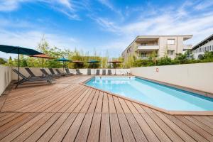 a pool with chairs and umbrellas on a wooden deck at Virginia N302 - 2p4 in Grasse