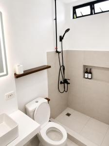 a bathroom with a white toilet and a shower at Hideout Siargao in General Luna +35 photos