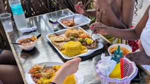 a group of people sitting around a table eating food at Baba Lao Beach Hostel in Malindi +49 photos