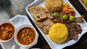 a plate of food with meat and rice and two sauces at Baba Lao Beach Hostel in Malindi