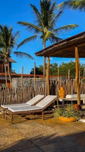a wooden gazebo with two beds and palm trees at Casa Monã in Maceio