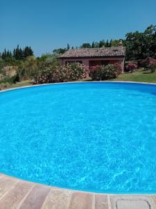 a large blue swimming pool with a house in the background at Casa Rustica mit privatem Pool zur alleinigen Nutzung in Corinaldo