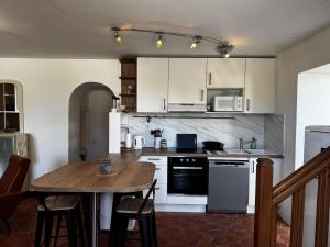 a kitchen with white cabinets and a wooden table at Holiday Home La houle by Interhome in Cancale +24 photos