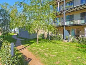 a tree in front of a building with a sidewalk at Apartment Seewind by Interhome in Lembruch