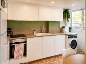 a kitchen with white cabinets and a sink and a dishwasher at Gran piso cerca del mar in Puerto de Gandía
