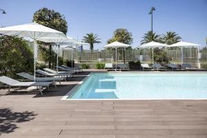 a swimming pool with lounge chairs and umbrellas at Grand Hotel in Forte dei Marmi