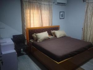 a bedroom with a bed and a chair and a window at Edo Global Boutique apartment in Benin City