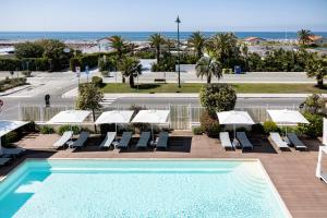 a swimming pool with chairs and umbrellas and the ocean at Grand Hotel in Forte dei Marmi