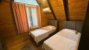 two beds in a small room with a window at Lefkali HOME in Çınarlık