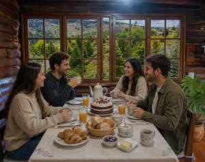 a group of people sitting around a table with a cake at Cabañas San Michele in La Cumbrecita