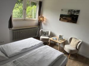 a bedroom with a bed and a chair and a table at Die Heilsbach gGmbH in Fischbach