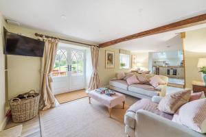 a living room with two couches and a tv at Puddle Cottage in Dorchester