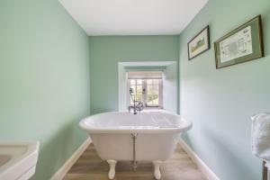 a white bath tub in a bathroom with a window at Puddle Cottage in Dorchester +25 photos