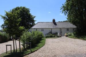 a white house with a gravel driveway in front of it at Puddle Cottage in Dorchester