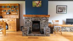 a stone fireplace in a living room with a table and chairs at Crab Cottage - Portmagee in Lateeve