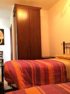 a bedroom with two beds and a wooden cabinet at affittacamere casaGiarelli&Battistini in Monti di Licciana Nardi
