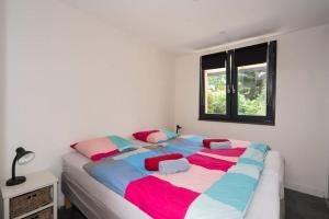 a bedroom with a large bed with colorful sheets at Bremerberg bungalow 50 in Biddinghuizen