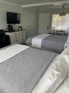two beds in a bedroom with a tv and a dresser at The Conch House Marina Resort in St. Augustine