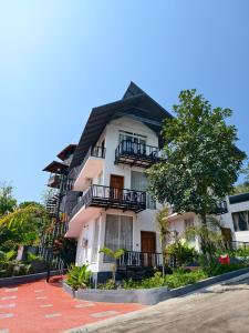 a white building with balconies and a tree at Coorg Tiger Eye Backwater Resort in Kushālnagar