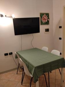 a green table with chairs and a flat screen tv on a wall at Il Nido in Costa Masnaga