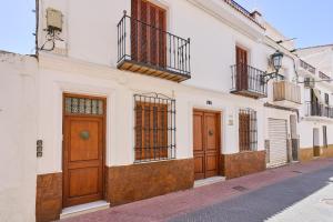 a white building with wooden doors on a street at Vivienda junto a Plaza España in Nerja