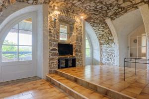 a living room with a stone wall and a fireplace at Le Mas Boyer in Chauzon
