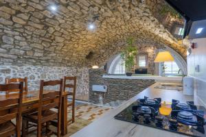 a kitchen with a table and a stone wall at Le Mas Boyer in Chauzon