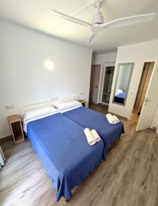 a bedroom with a blue bed with two towels on it at Hostal Sol de Mallorca in El Arenal