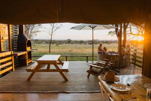 a group of people sitting at a table on a deck at AfriCamps Waterberg in Vaalwater