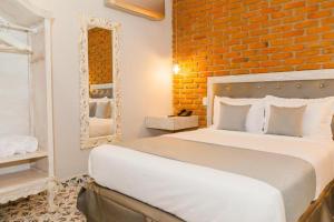 a bedroom with a white bed and a brick wall at Hotel Boutique ADAZ in Santa Marta